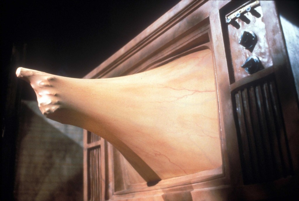 A finger points out of a fleshy TV screen in a shot from David Cronenberg's Videodrome (1983)