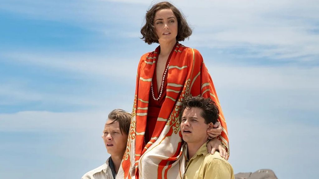 Ana de Armas in an orange shawl being carried by two men in a shot from Eden (2025).