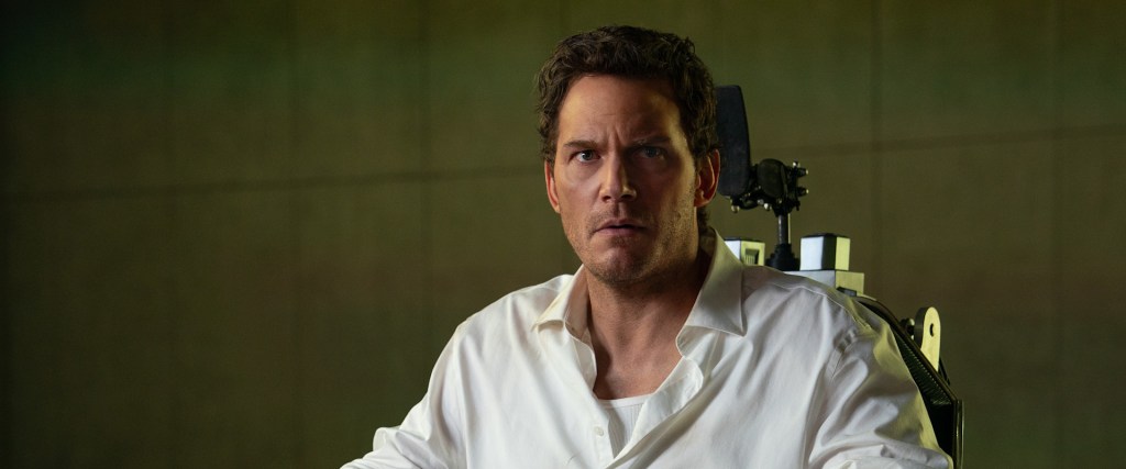 Chris Pratt sits in a chair and looks offscreen in a scene from the movie Mercy (2026).