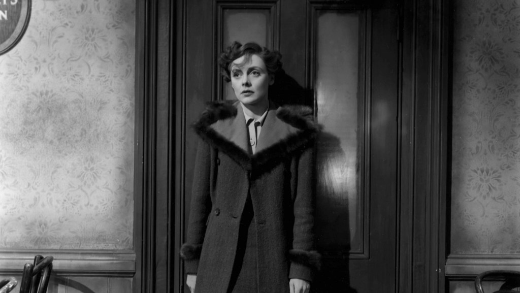 Celia Johnson stands in front of a door looking distraught in a black-and-white image from Brief Encounter (1945).