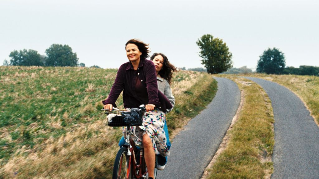 Two women ride a bicycle together through the French countryside in a scene from Miroirs No. 3.